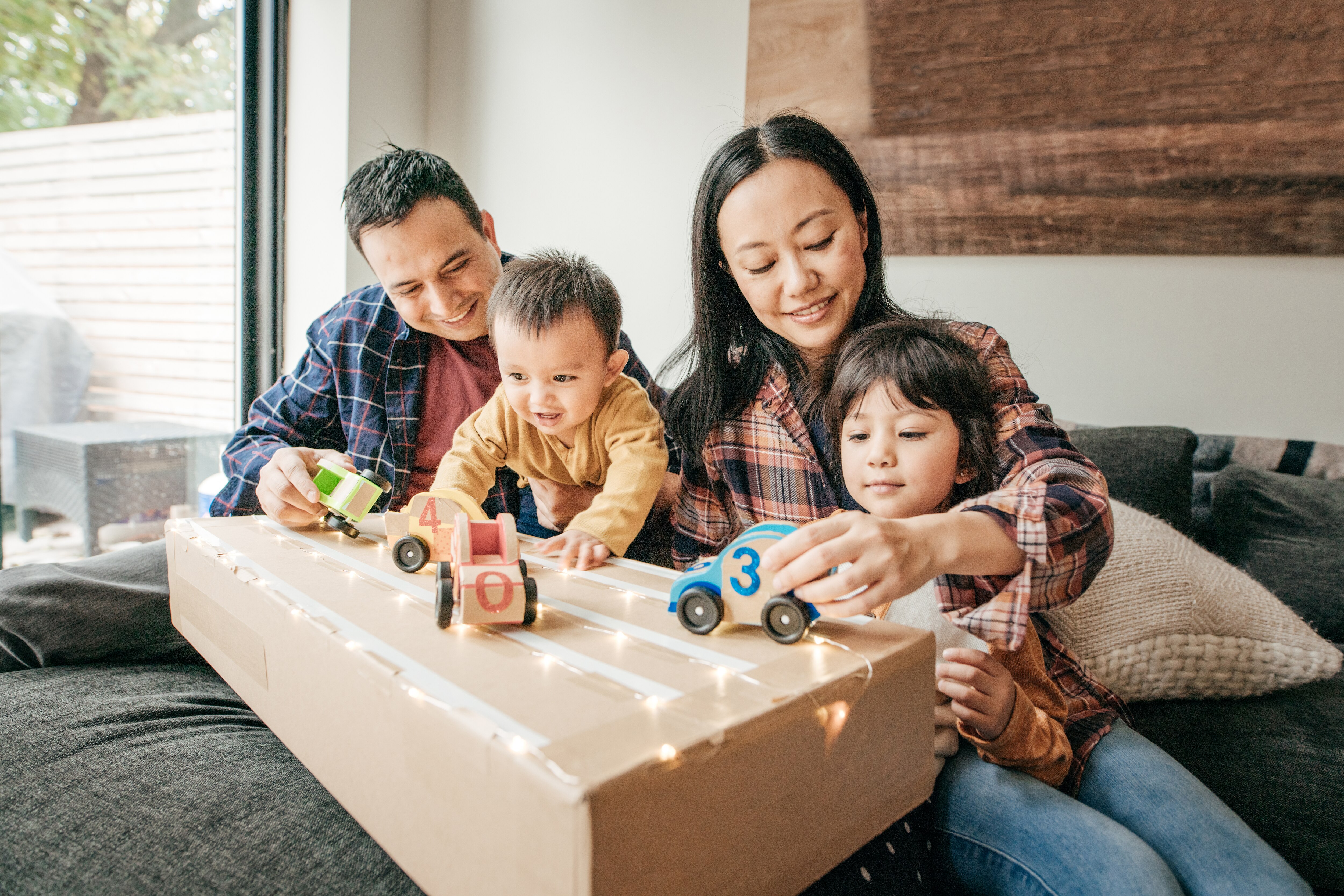 Man, woman, and two children playing with toy cars