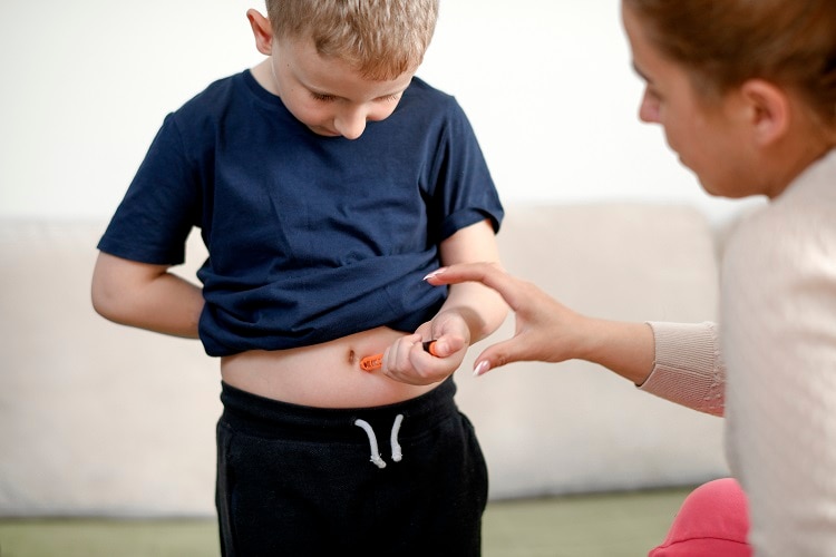 Boy self-administering insulin shot.
