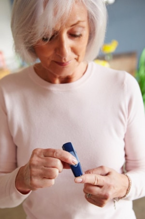 White-haired woman checking her blood sugar.