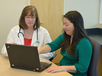 A female doctor and another female behind a laptop