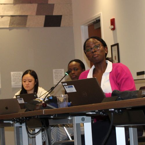 Fellows sitting at desks and listening to a speaker.