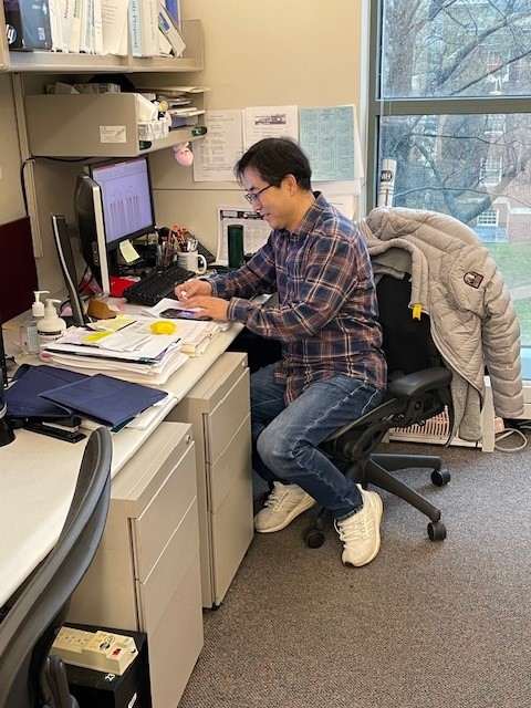 HeungSun Kwon using his phone while sitting at his desk.
