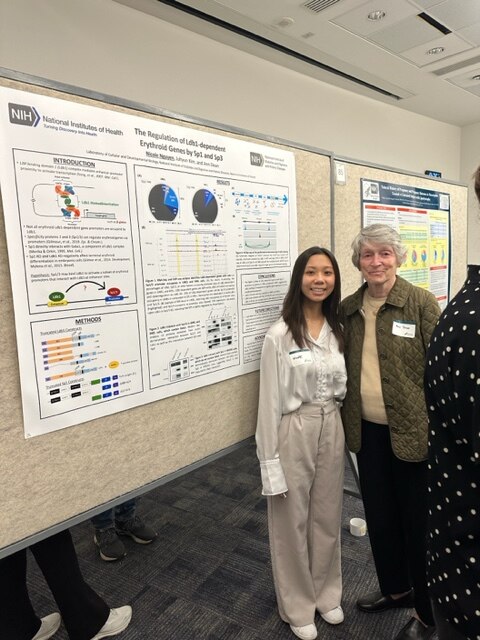 Nicole Nguyen and Ann Dean standing in front of a poster and smiling.