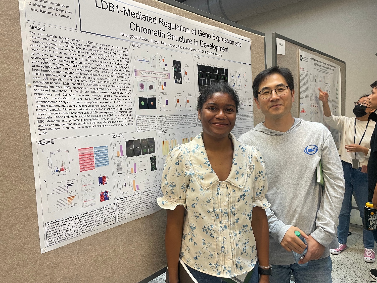 Shinelle Black and HeungSun Kwon standing in front of a poster and smiling.