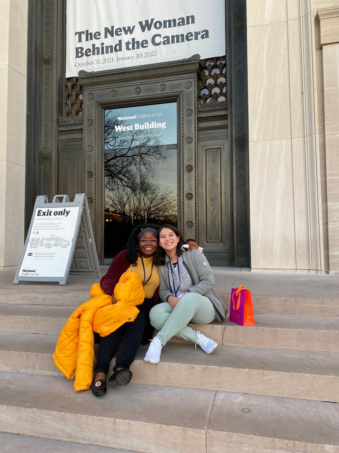 Kanyin and Nicole sitting on the steps of the National Gallery of Art west building. 