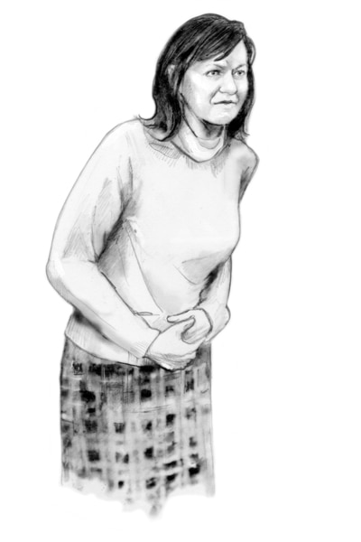 A woman standing and clutching her abdomen with both hands.
