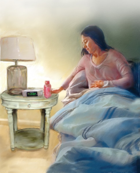 A woman sitting in bed with her hand on her abdomen in discomfort. She’s reaching for a bottle of liquid medicine on her nightstand.