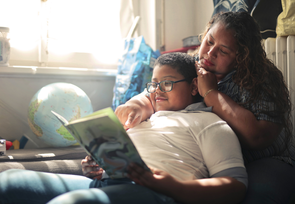 Madre e hijo leyendo un libro juntos en casa.