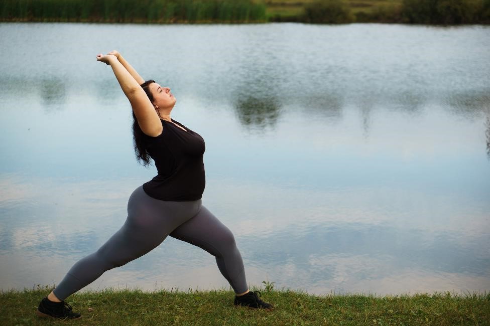 Overweight woman practicing yoga in a park.
