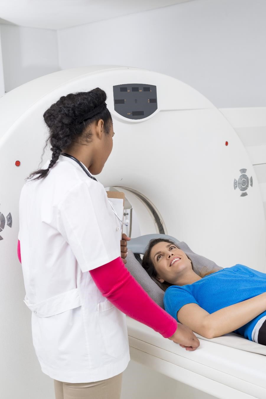 A female health care professional prepares a female patient for an MRI exam.