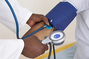 A photo showing a close-up of a health care provider checking a patient’s blood pressure.