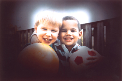 This photo shows how glaucoma affects vision. Shadows darken all sides of a view of two boys. Only the center is bright enough to see clearly.