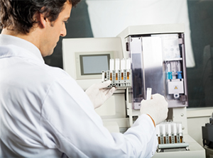 Image of a lab technician analyzing viles of red blood cells.