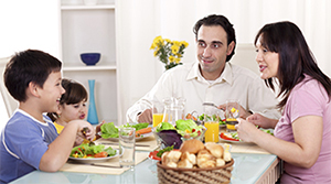 Family sitting at the family table eating a healthy meal.